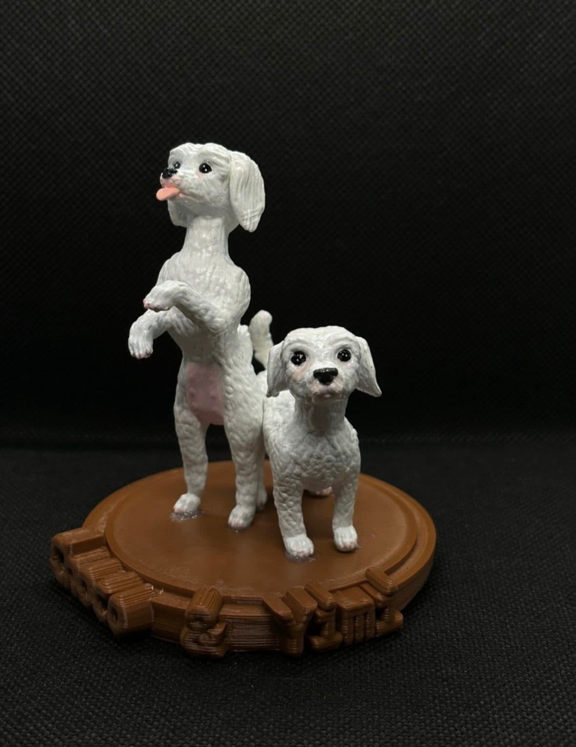Figura de dos perros blancos, uno de ellos parado en dos patas, sobre una base de madera.