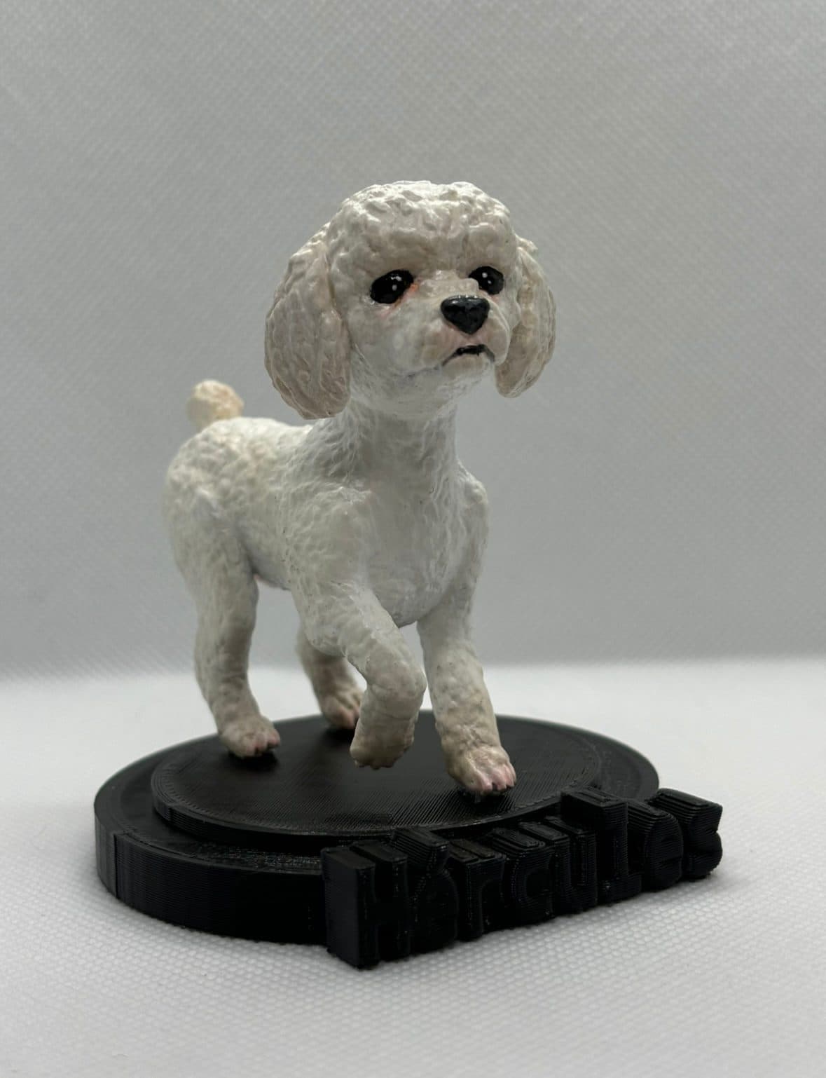 Figurita de un poodle blanco sobre una base negra.