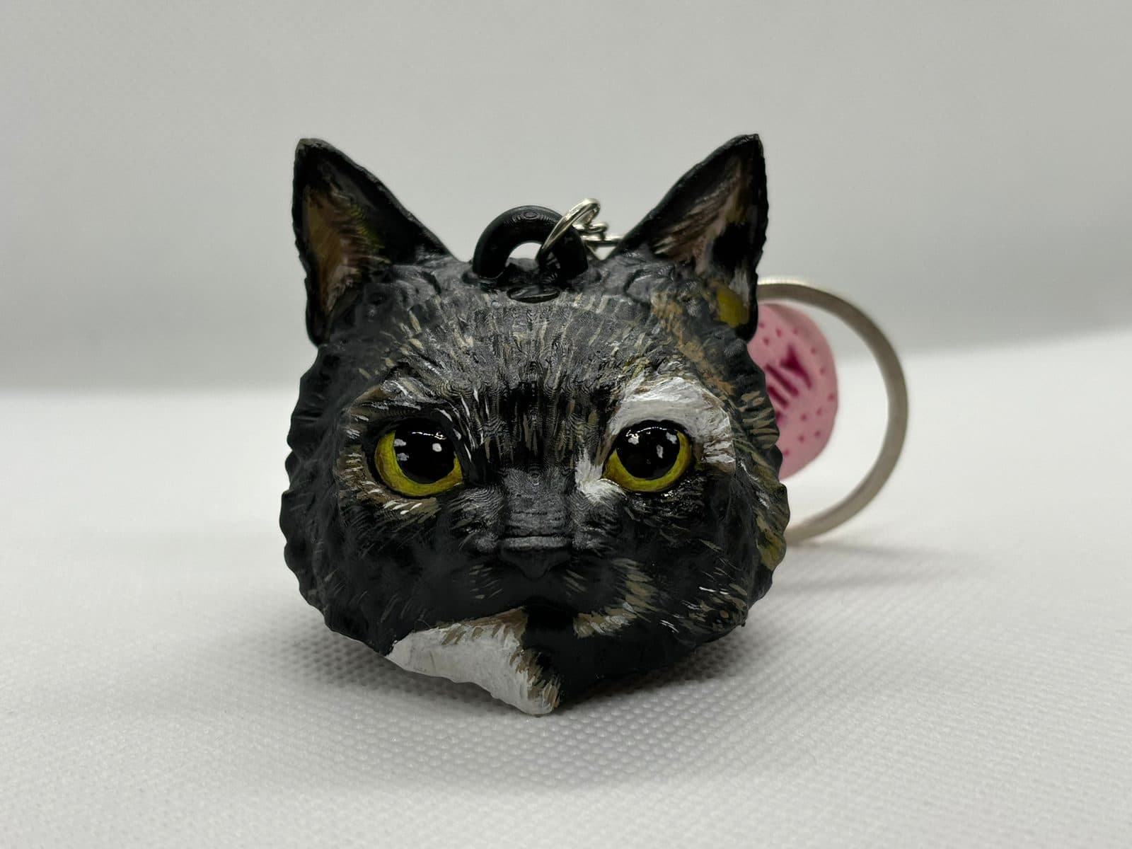 Llavero con la carita de una gata carey de ojos amarillos, pintada a mano.