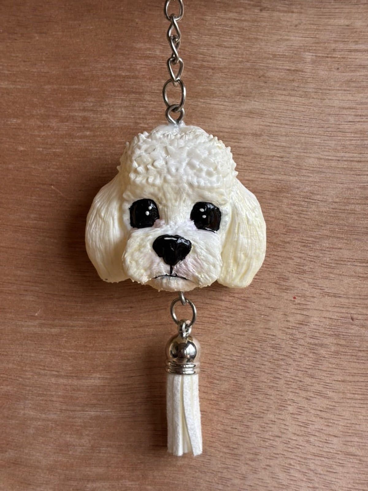 Llavero pintado a mano de un caniche blanco de pelaje texturado, con borla blanca.
